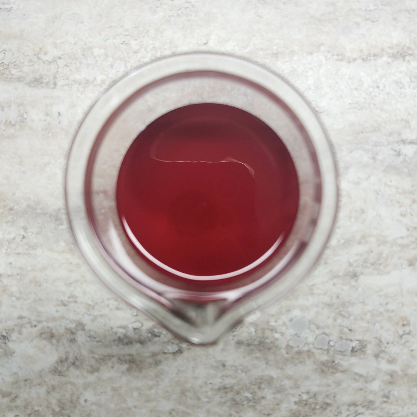 Christmas Red liquid colorant for soap and cosmetics in a glass beaker at Wixy Soap